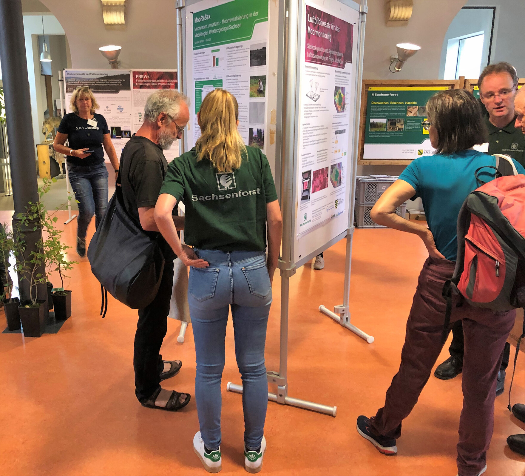 Besucher und Standbetreuer diskutieren vor Schautafeln.